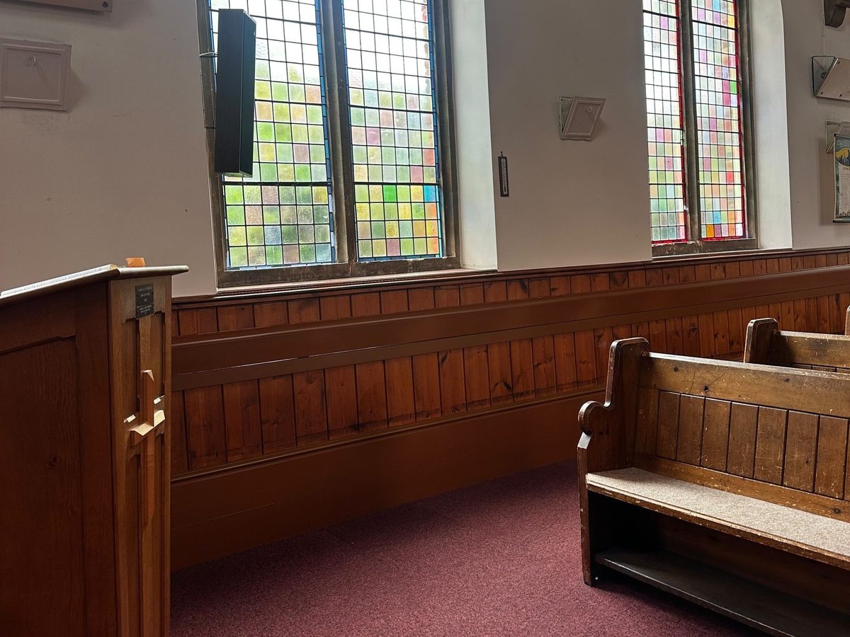 Heated skirting and mid-panel tiers continuing past the pulpit beneath stained glass windows