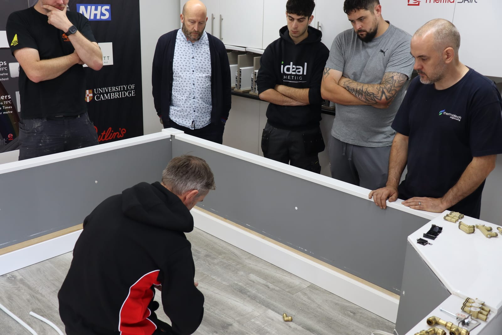 Installers gathered around a ThermaSkirt mock-up wall during a hands-on training session at the Atherton, Manchester factory