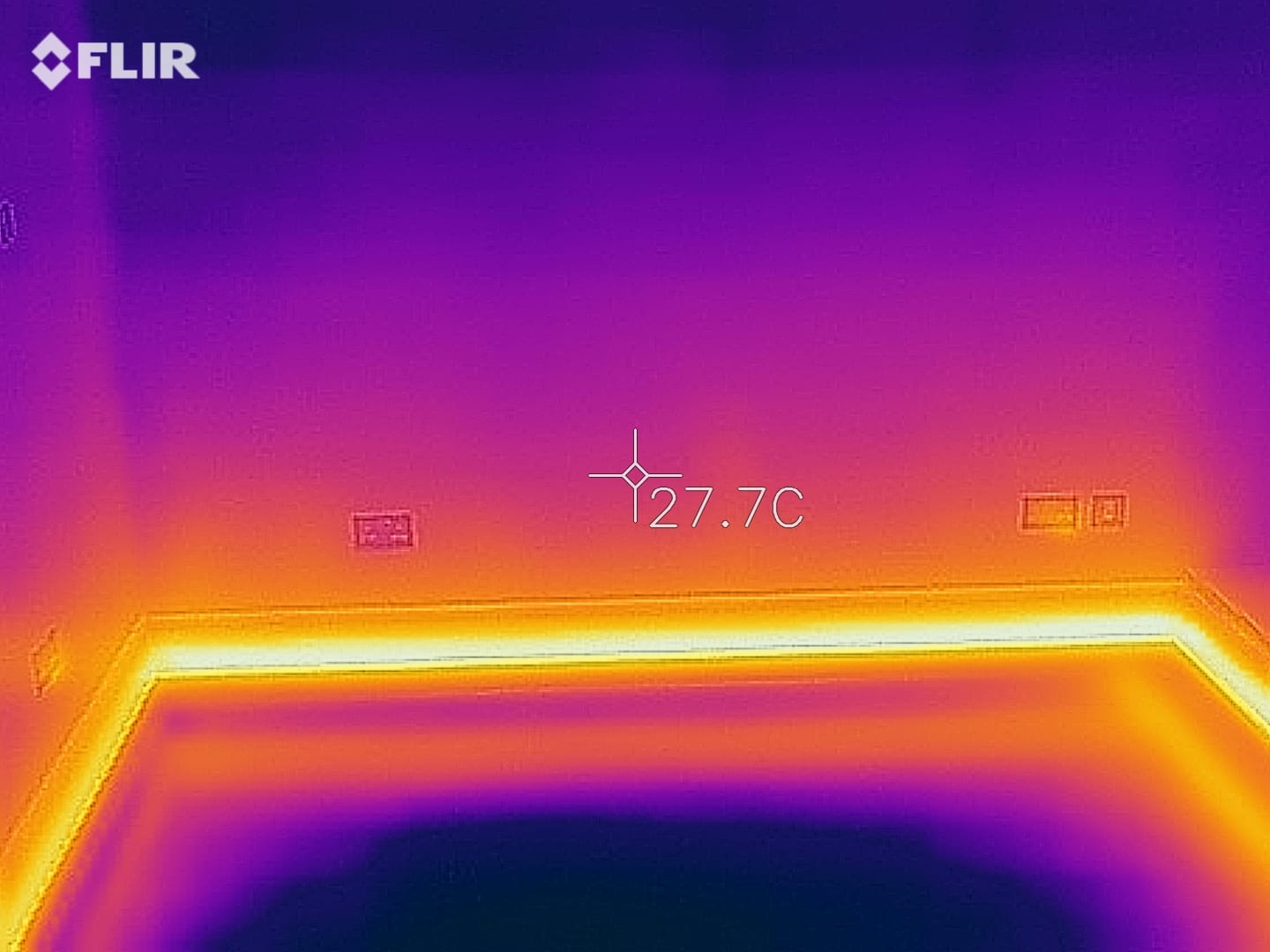 Thermal camera image of ThermaSkirt glowing warm around a room perimeter