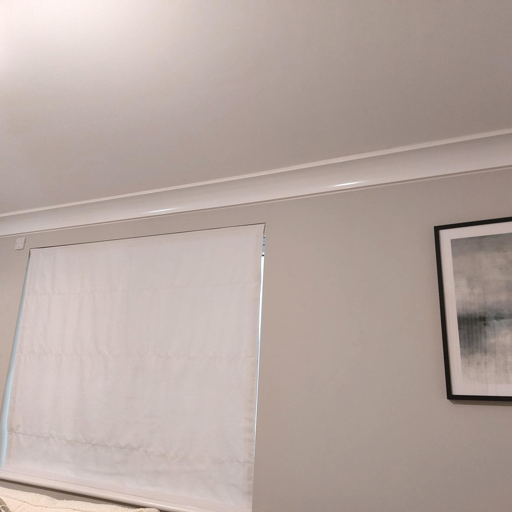 ThermaCurve mounted at the wall-ceiling junction of a modern room, almost indistinguishable from the coving